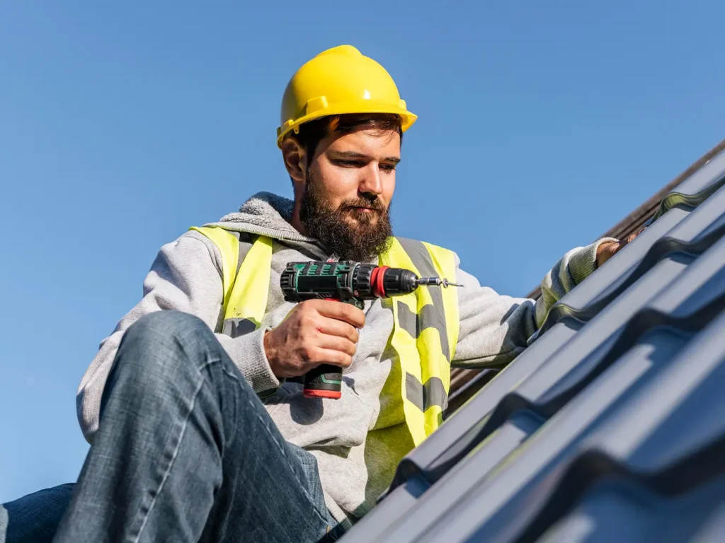 Worker fixing damaged slate tiles on a roof, front perspective.