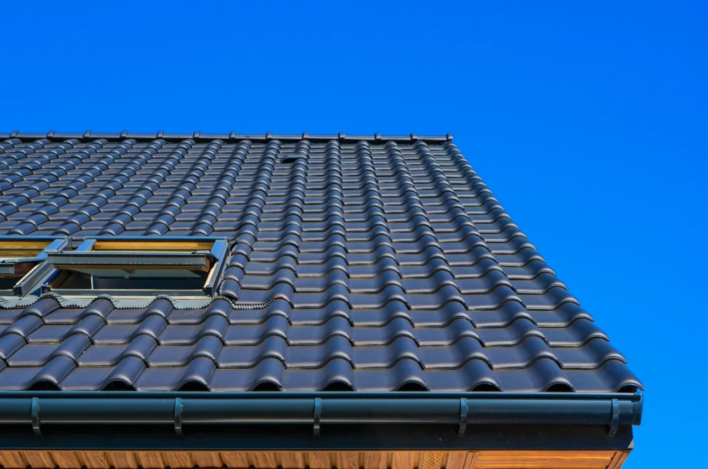 Storm damage roof repair Boston image showing missing asphalt shingles and exposed roof areas after strong wind and rain. 