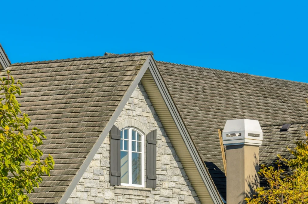 Stone home with a well-maintained roof, highlighting how regular roof inspection helps homeowners catch small issues before they become costly repairs