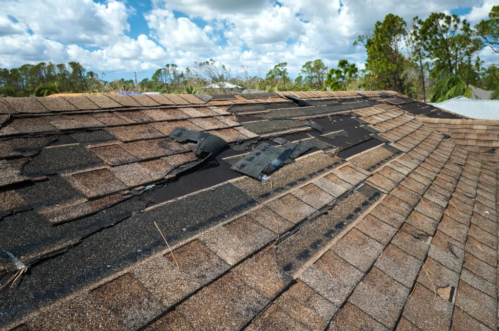 Missing shingles on damaged roof show where emergency roof leak repair may be needed before water reaches inside the home. 