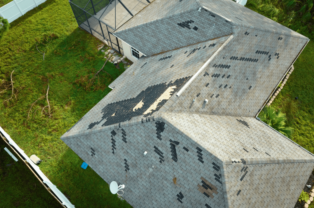 Aerial view of a storm-damaged roof with missing shingles and exposed areas found during a professional roof inspection.