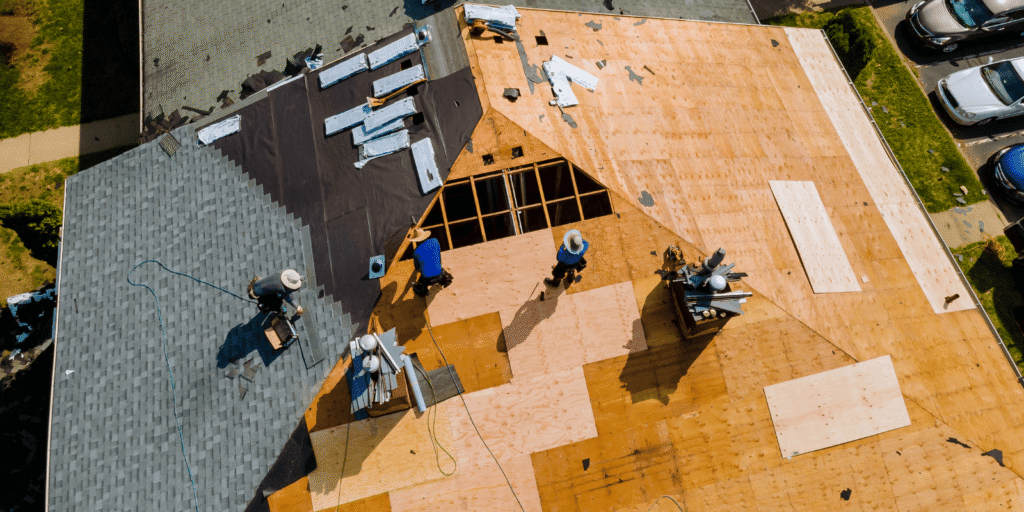 Roofers replace old roofing and prepare new decking during a professional roof installation and replacement project in Boston