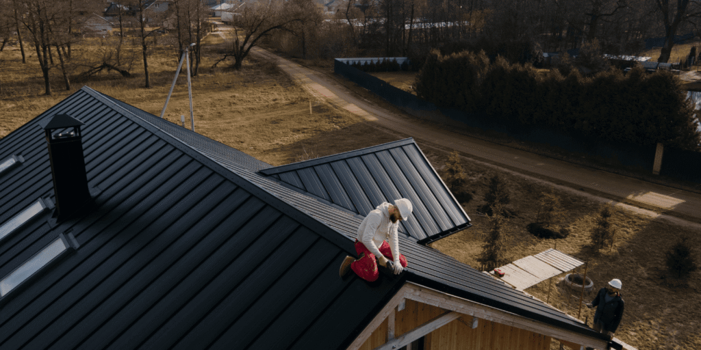 Roofer checks a residential metal roof during a professional inspection for regular roofing maintenance planning in Boston.