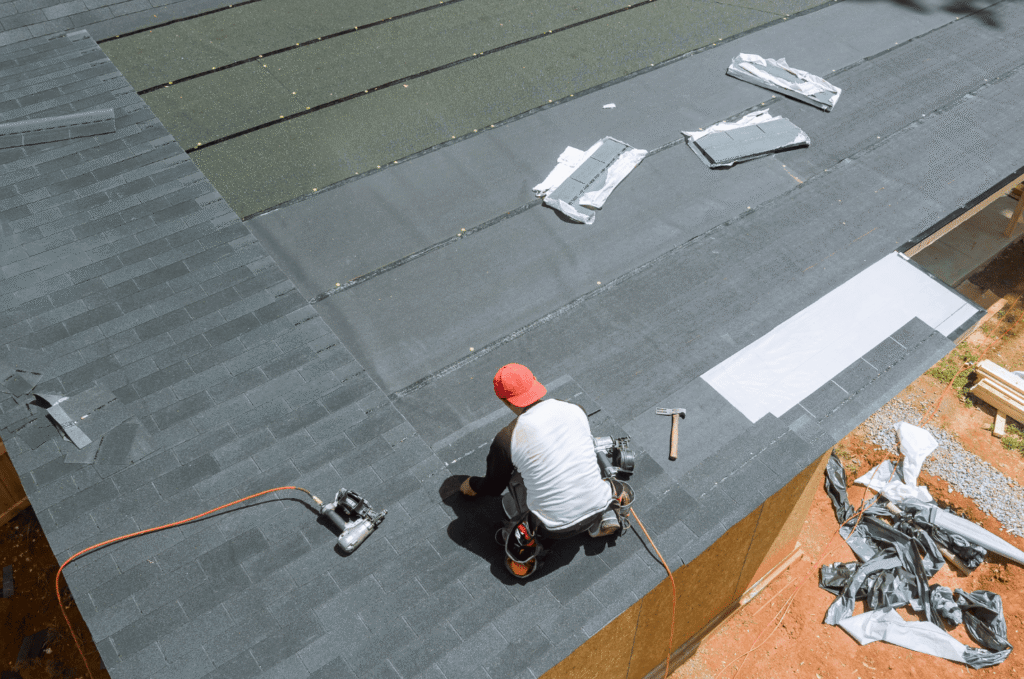 Roofer installs asphalt shingles on a residential roof during a professional roof installation project in Boston.