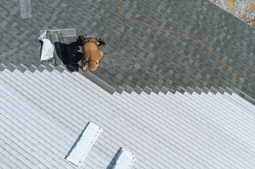 Roofer works on a residential shingle roof after inspection findings guide regular roofing maintenance and repair planning.