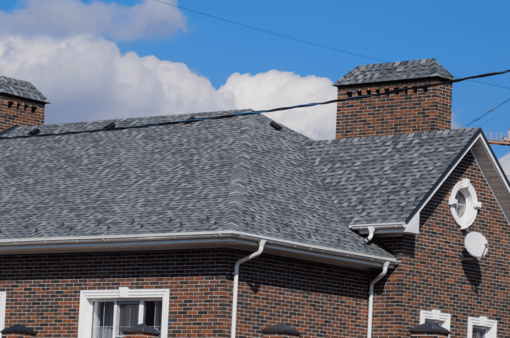 Asphalt shingle roof with gutters and chimney areas reviewed during a seasonal roof maintenance checklist for a brick home.