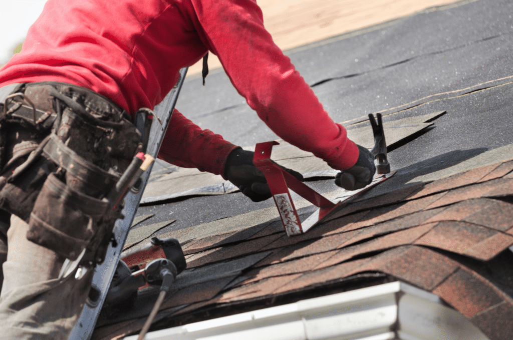 Roofer checks worn shingles during Boston roof replacement after repeated leaks show repair may no longer be enough for home.
